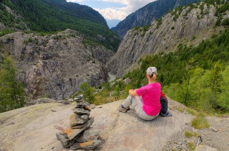 young fit woman enjoys view over Aletsch valley with Belalp Riederalp Gruensee suspension bridge down below, Switzerlandの写真素材
