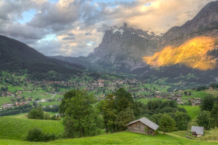 Famous alpine town Grindelwald in valley at sunset in front of mountain Eiger north face, Switzerlandの写真素材