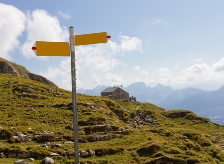summer mountain landscape with hiking signpost, meadows and guesthouse, concept for directions, Switzerlandのeditorial素材