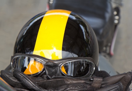 vintage safety gear for motorbikes and convertible cars consisting of leather gloves, helmet and pilot goggles on bike seatの写真素材