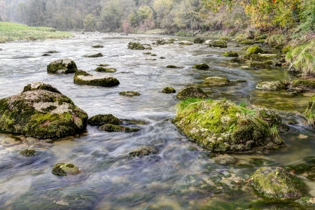 fresh. clean, clear, forest stream splash down over moss covered stones in autumn woodsの写真素材