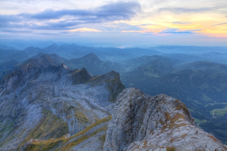 panrama of high alpine ragged sharp karst mountain top ranges disapear in misty distance and green meadow at sunset, Switzerland の写真素材