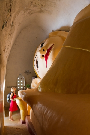 Giant Reclining Buddha with tourist woman at Manuha Paya in Bagan, Burmaの写真素材