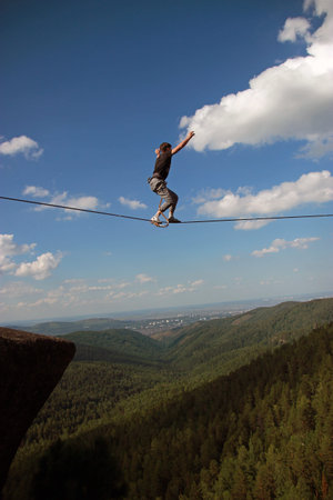 A young man rope Walker balancing over the abyss.