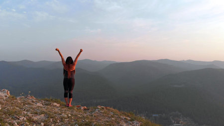 Young happy woman standing on the edge of a cliff. Aerial shot, 4K