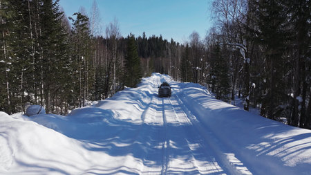 Off-road vehicle driving on snowy forest road in winter