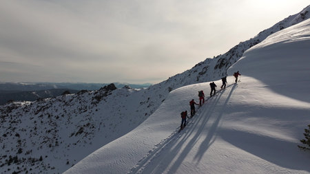 Adventurers climbing snowy mountain ridge in scenic winter landscape