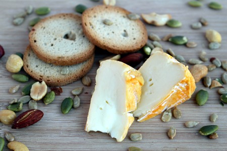 Cheese snack with crackers and mixed nuts on a wooden boardの写真素材