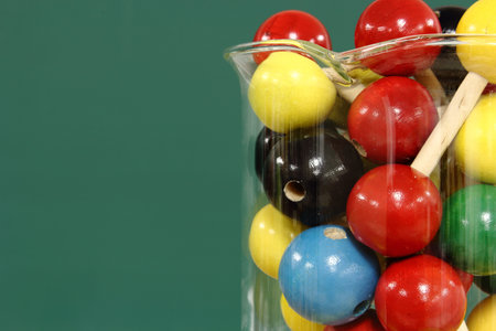 Molecular model: wooden balls in a beaker on a background of green blackboard