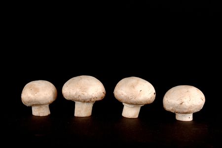 Four fresh cuted champignons isolated on black background.の写真素材