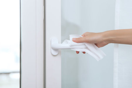 Cleaning door handles with an antiseptic wet wipe and gloves. Woman hand using towel for cleaning...