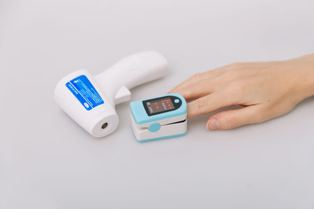 Pulse oximeter and thermometer gun on white background. Measuring oxygen saturation, pulse rate and...