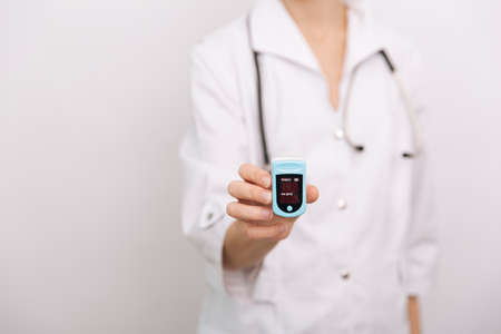 Pulse oximeter with hand of doctor isolated on white. The concept of portable digital device to measure persons oxygen saturation. Measuring oxygen saturation, pulse rate and oxygen levelsの写真素材