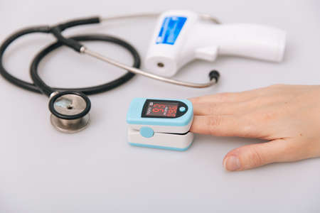 Stethoscope, pulse oximeter and thermometer gun on white background. Treatment of cold or flu. Phonendoscope. Infrared isometric thermometer gun to check body temperature for virus symptomsの写真素材