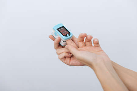Pulse oximeter with hand of doctor isolated on white. The concept of portable digital device to measure persons oxygen saturation. Measuring oxygen saturation, pulse rate and oxygen levels.の写真素材