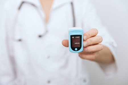 Pulse oximeter with hand of doctor isolated on white. The concept of portable digital device to...