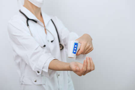 Temperature measurement gun in doctor hands. Close-up shot of doctor wearing protective surgical mask ready to use infrared isometric thermometer gun to check body temperature for virus symptomsの写真素材