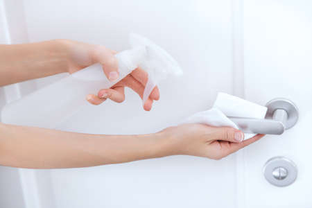 Cleaning white door handles with an antiseptic wet wipe and sanitizer spray.の写真素材
