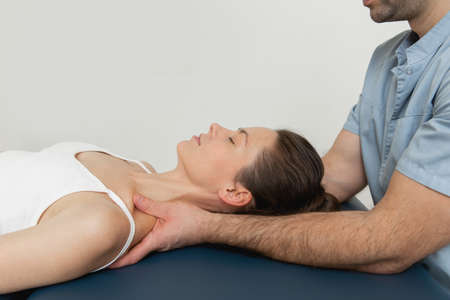Female patient receiving osteopathic neck and shoulder treatment. Therapist manipulating back of head and chest. A girl receiving CST treatment. Osteopathic manipulation and therapyの写真素材