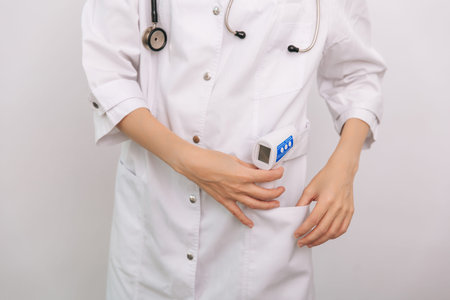 Temperature measurement gun in doctor hands. Close-up shot of doctor wearing protective surgical...