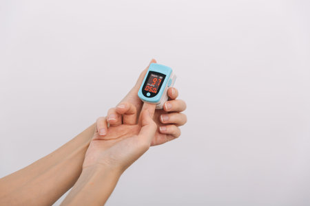 Pulse oximeter with hand of doctor isolated on white. The concept of portable digital device to...
