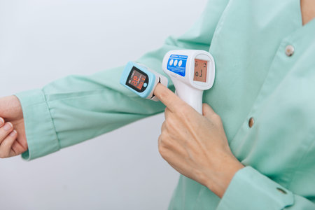 Temperature measurement gun in doctor hands. Close-up shot of doctor wearing protective surgical...