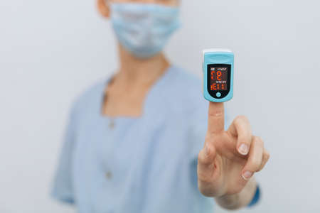 Pulse oximeter with hand of doctor isolated on white. The concept of portable digital device to measure persons oxygen saturation. Measuring oxygen saturation, pulse rate and oxygen levels.の写真素材