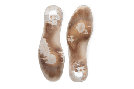 Two old, shabby orthopedic insoles isolated on white background. Dirty leather insoles. Worn out things with holes. Inner soles of shoes. Top view banner close upの写真素材