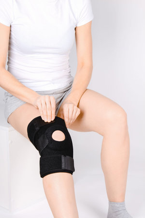Knee Support Brace on leg isolated on white background. Elastic orthopedic orthosis. Anatomic braces...