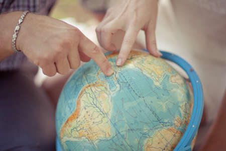 Woman and businessman using world map interface point to globe. Planet earth globe. Top view of America. Travel concept. Holidays. A young couple is planning a honeymoon vacation trip with a mapの写真素材
