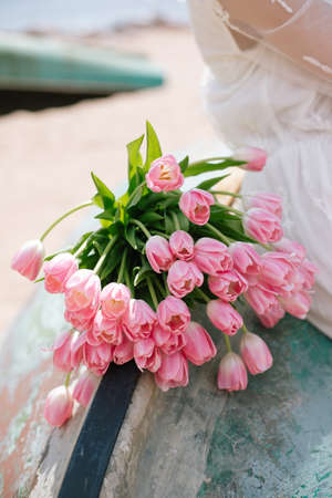 A bouquet of pink tulips on a girl lap. Wedding romantic concept for banner or card. Mothers day, Valentines Day, Birthday celebration concept. Greeting card. Copy space for textの写真素材