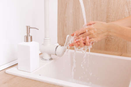 Washing hands under the flowing water tap. Washing hands rubbing with soap for corona virus prevention, hygiene to stop spreading corona virus in or public wash room. Hygiene concept hand detailの写真素材