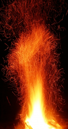 A campfire with sparks rising into the night の写真素材