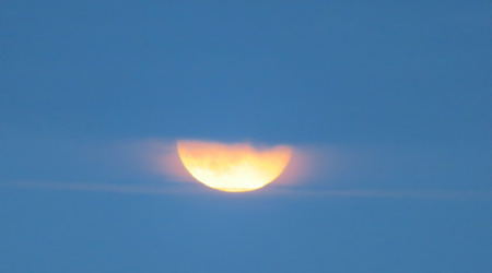 Orange Moon Rising At Dusk Behind The Cloudsの写真素材