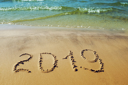 2019 written on the sand, sea surf. Concept for New year greetings. Seaside natural background with...