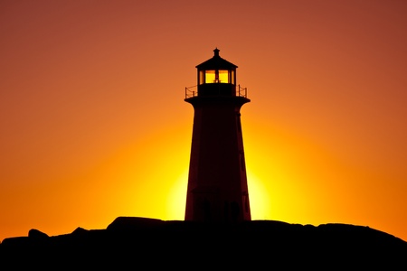 Peggy's Cove lighthouse silhouetted against an orange-coloured sky at sunset, Nova Scotia.の写真素材