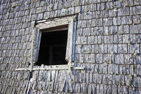 Empty window frame on a weathered barn wall.の写真素材