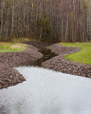 Rocky banks of a serpentine creek as it flows through a rural landscape の写真素材