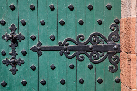 Ornate wrought iron hinge on a heavily iron-studded castle door.