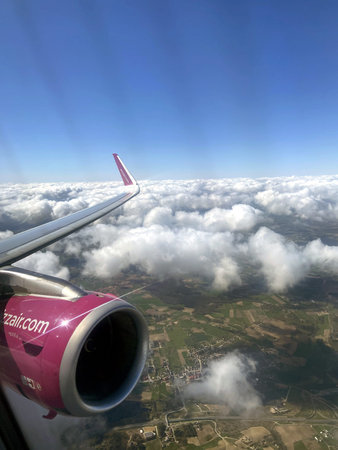 View from the window of an airplane flying in the blue sky with clouds