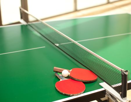 Two table tennis or rackets and balls on a green table with netの写真素材