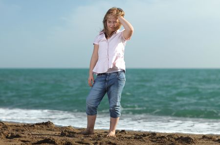 Blonde young girl with shirt and blue jeans on the beach; shallow depth of fieldの写真素材