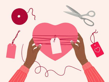 Valentine's day concept. Black female hands hold gift box wrapped into kraft paper. Top view table with romantic eco-friendly packaging, hearts, ribbon, scissors. Hand drawn vector illustrationのイラスト素材