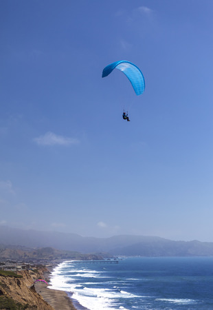 This is an image of a paraglider over Muscle Beach along Californias central coast.  Muscle beach is located in Pacifica, California, which is a prime spot for paragliding due to its fantastic weather conditions and views.の写真素材