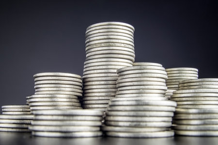 Stacks of coins different height close up in front of the camera. A perfect abstract illustration of money, income, economy. Stacks of silver nickel coins very close up in front of camera.の写真素材