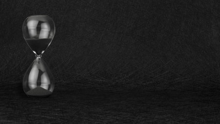 Black sand clock timer hourglass on black textured background.の写真素材
