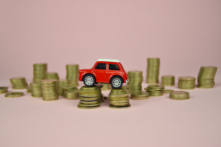 Red car toy on stacks of coins. Pink background. Close up. Red car toy on stacks of coins. Pink background.の写真素材
