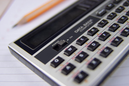Portable vintage calculator on a notepad notebook with a lead graphite sharpened pencil next to it.