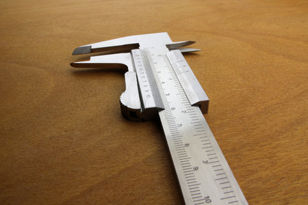 Caliper device measuring on wooden background. Vernier caliper on wood background, closeup of photoの写真素材