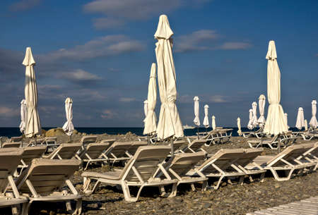 pebble beach with sunbeds and umbrellas against the blue skyの写真素材